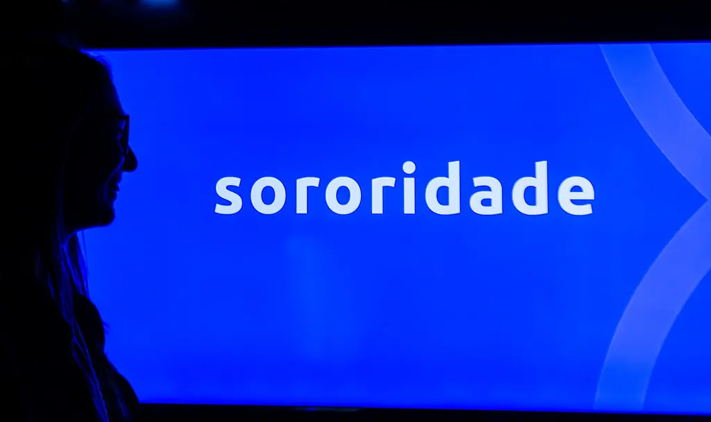 Silhueta de espectadora diante de tela azul com a palavra sororidade